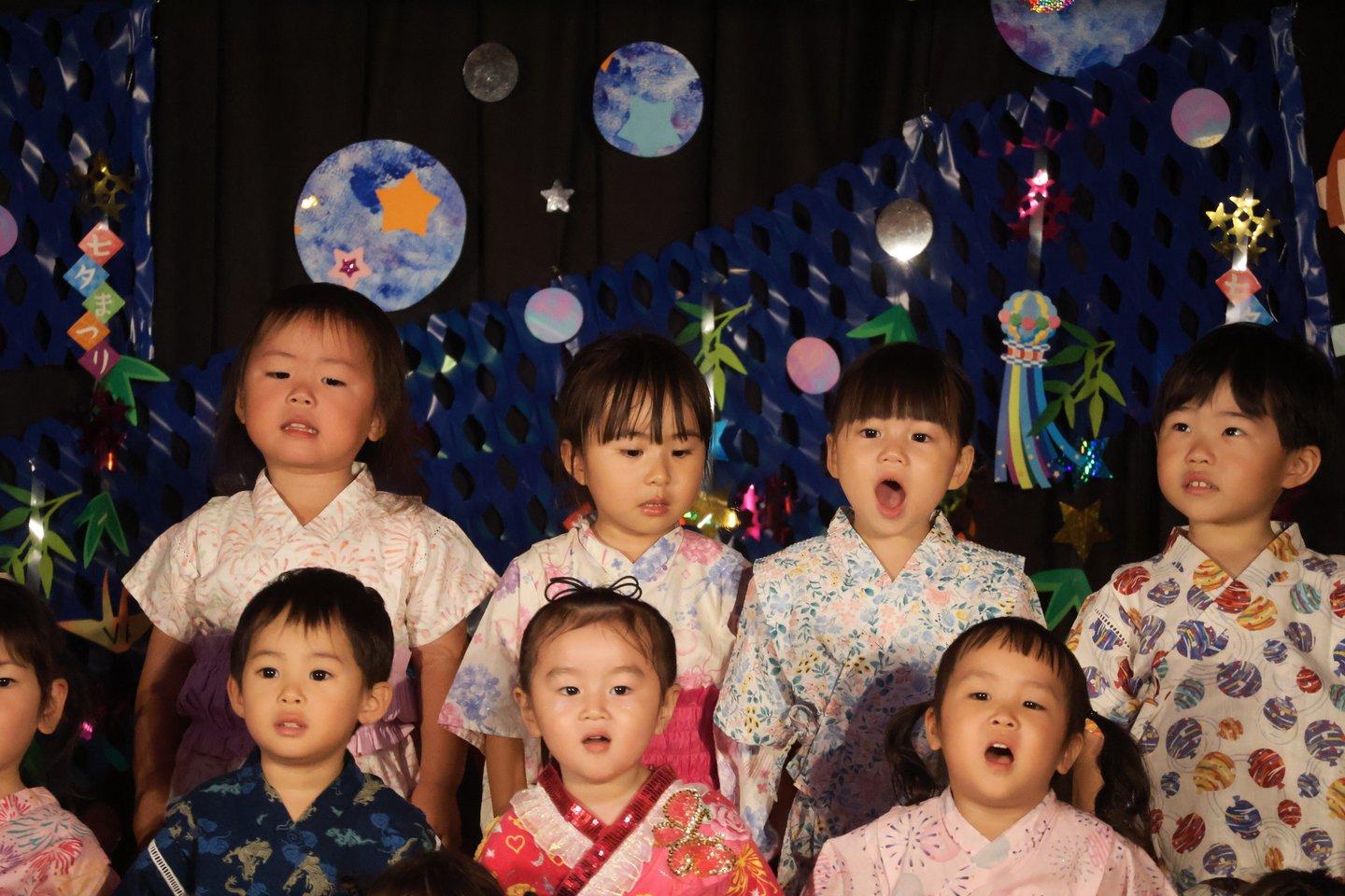 七夕飾りのある舞台で、子どもたちが発表している場面。
